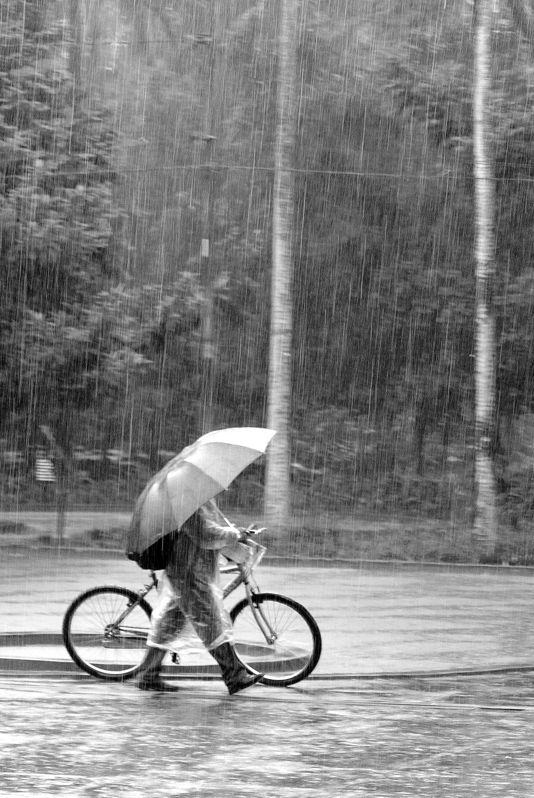 Promeneur en vélo sous la pluie.